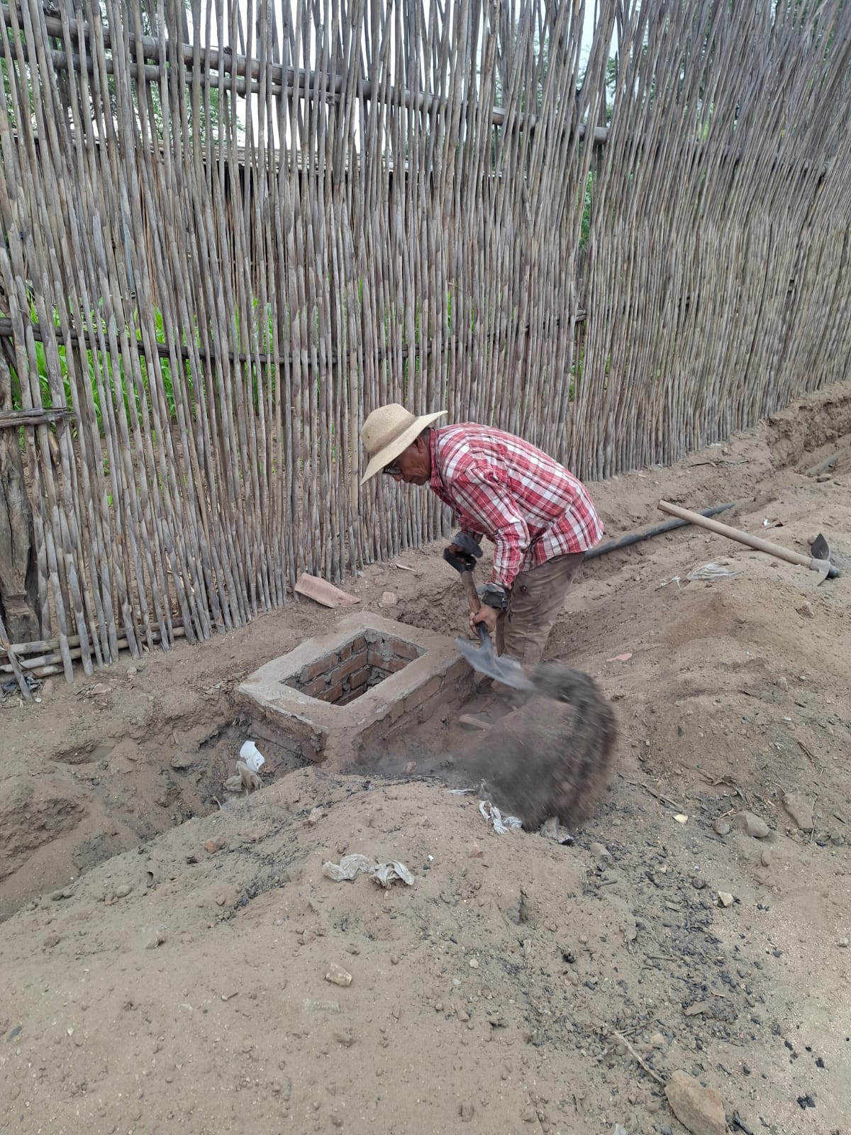 Trabajador profundizando con pala el pozo de captación de ladrillo.